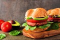 Plant based meatless burgers with avocado, tomato and spinach against a dark background Royalty Free Stock Photo