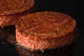 Plant based vegetarian burger patties being cooked on flat black iron grill