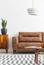 Leather couch in white apartment interior with wooden table. Real photo Royalty Free Stock Photo