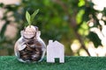 Plant growing from coins in glass jar. Wooden house model on artificial grass. Home mortgage and property investment concept Royalty Free Stock Photo