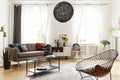 Plant next to couch and sunflowers on cabinet in white flat interior with armchair and lamp. Real photo