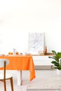 Plant and poster on cabinet in white dining room interior with chair at table with orange cloth Royalty Free Stock Photo