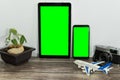 Plant, a tablet and a phone with green screens, a camera and a toy plane on wooden background Royalty Free Stock Photo