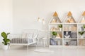 Plant and white chair next to bed in kid`s bedroom interior with