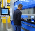 At the plant. Worker holding the metal sheet working with the CNC hydraulic press brake machine, the board of computer Royalty Free Stock Photo