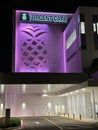 Night photo of the neon lit Baptist Urgent care in Plantation FL