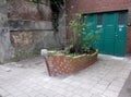 Planter in the form of a boat made of bricks in front of a garag