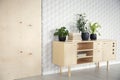 Plants and books on wooden cupboard in natural living room interior with wallpaper. Real photo Royalty Free Stock Photo