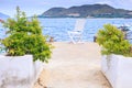 Plants in Pots Chair on Stone Pier Sea Distant Hill Island Royalty Free Stock Photo
