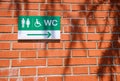Plaque indicating the direction of disabled toilets on a brick wall Royalty Free Stock Photo