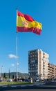 A huge flag of spain flutters its colors in the wind in a roundabout