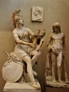Plaster copy of two ancient sculptures, one of a woman with a shield and musical instrument, the other of a child, located in the