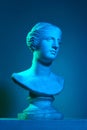 Plaster copy of Venus statue. Gypsum antique statue bust against blue studio background in neon lights. Concept of art