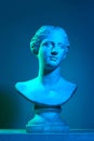 Plaster copy of Venus statue. Gypsum antique statue bust against blue studio background in neon lights. Concept of art