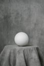 Plaster white sphere or ball, on a gray fabric artistic background. Royalty Free Stock Photo