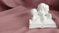 Plaster white statuette of two angels reading a book Royalty Free Stock Photo