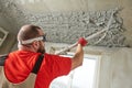 Plasterer using sprayer machine putting plaster mortar on ceiling