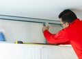 Plasterboard worker installs a plasterboard wall on the kitchen cabinets to cover the extractor pipe of the hood Royalty Free Stock Photo