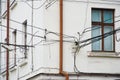 The plastered facade of an old house. Plenty of entangled electrical wires near windows and a drainpipe. Problems of ill-conceived Royalty Free Stock Photo