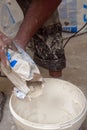 Plasterer in dirty uniform is pours dry cement into the bucket. Credible photos