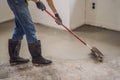 plasterer during floor covering works with self-levelling cement mortar, uses a needle roller