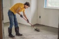 plasterer during floor covering works with self-levelling cement mortar, uses a needle roller