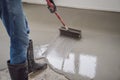 plasterer during floor covering works with self-levelling cement mortar, uses a needle roller