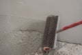 plasterer during floor covering works with self-levelling cement mortar, uses a needle roller