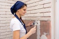 Plasterer girl plasters a wall, laying out imitation brickwork