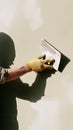 Plasterer hand holding trowel applying waterproof plaster on wall. Construction worker in yellow gloves doing renovation work. Royalty Free Stock Photo