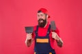 Plasterer hipster builder in cap red background. Interior designer. Bearded man worker with plastering tools