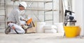 Plasterer man construction worker work with tool box wear gloves, hard hat and protection glasses at interior building site with Royalty Free Stock Photo