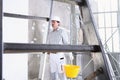 Plasterer man work holds a bucket front the wall of interior construction site wear helmet and protective gloves, ladder and Royalty Free Stock Photo