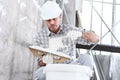 Plasterer man at work, take the mortar from the bucket to plastering the wall of interior construction site wear helmet and Royalty Free Stock Photo