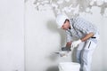 Plasterer man at work, take the mortar from the bucket to plastering the wall of interior construction site wear helmet and Royalty Free Stock Photo