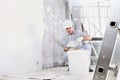 Plasterer man at work, take the mortar from the bucket to plastering the wall of interior construction site wear helmet and Royalty Free Stock Photo