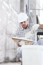 Plasterer man at work, take the mortar from the bucket to plastering the wall of interior construction site wear helmet and Royalty Free Stock Photo