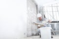 Plasterer man at work, take the mortar from the bucket to plastering the wall of interior construction site wear helmet and