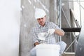 Plasterer man at work, take the mortar from the bucket to plastering the wall of interior construction site wear helmet and Royalty Free Stock Photo