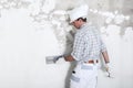 Plasterer man at work with trowel plastering the wall of interior construction site wear helmet and protective gloves, Royalty Free Stock Photo