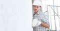 Plasterer man at work with trowel plastering the wall of interior construction site wear helmet and protective gloves, scaffolding Royalty Free Stock Photo