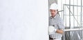 Plasterer man at work with trowel plastering the wall of interior construction site wear helmet and protective gloves, scaffolding Royalty Free Stock Photo