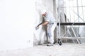 Plasterer man at work with trowel plastering the wall of interior construction site wear helmet and protective gloves, scaffolding Royalty Free Stock Photo