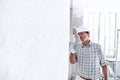 Plasterer man at work with trowel plastering the wall of interior construction site wear helmet and protective gloves, scaffolding Royalty Free Stock Photo