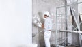 Plasterer man at work with trowel plastering the wall of interior construction site wear helmet and protective gloves, scaffolding Royalty Free Stock Photo