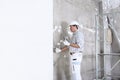 Plasterer man at work with trowel plastering the wall of interior construction site wear helmet and protective gloves, white wall Royalty Free Stock Photo