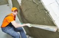 Plasterer smoothing fresh plaster on wall by straightedge trowel