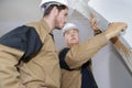 Plasterer teaching apprentice how to scrape wallpaper Royalty Free Stock Photo
