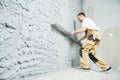 Plasterer using screeder smoothing putty plaster mortar on wall Royalty Free Stock Photo