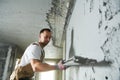 Plasterer using screeder smoothing putty plaster mortar on wall